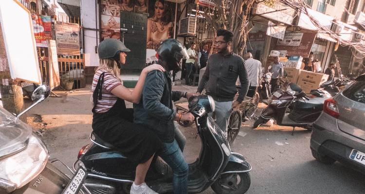 Mensen op een scooter die zich een weg banen door een drukke straat.