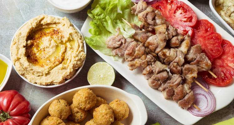 Verschiedene Gerichte aus dem Nahen Osten mit Hummus, Spießen und Gemüse.