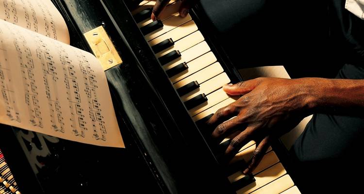 Close-up of hands playing a piano with sheet music.
