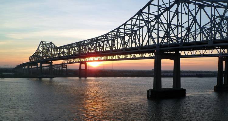 Bridge silhouette against a sunset sky over a river.