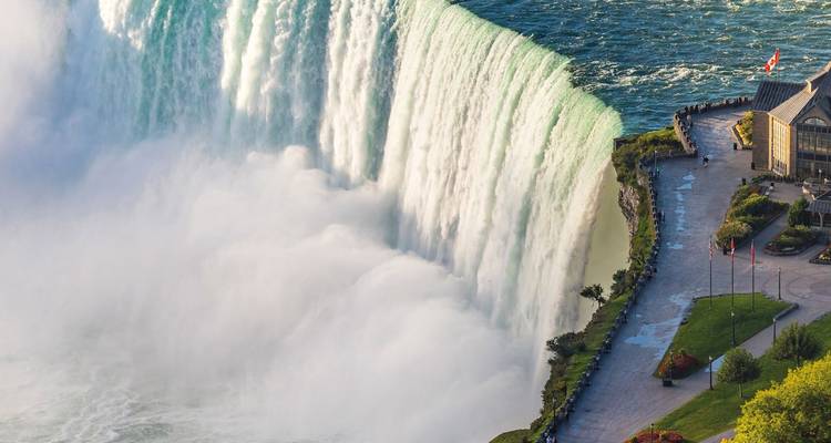 Majestueuze Horseshoe Falls van Niagara die in mist neerstorten met zichtbare rivierpromenade en bezoekerscentrum