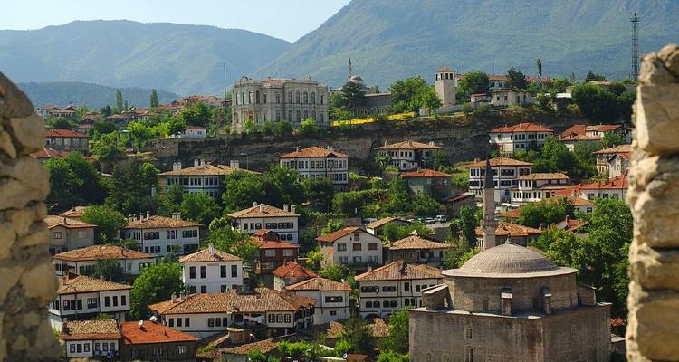 Casas otomanas pintorescas con techos de tejas rojas apretujadas densamente en la ladera de Safranbolu bajo montañas lejanas.
