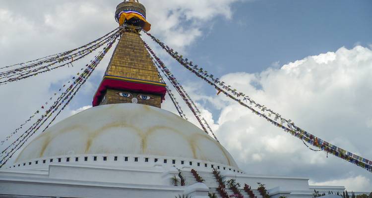De Boudhanath Stupa met gebedsvlaggen tegen een blauwe lucht.
