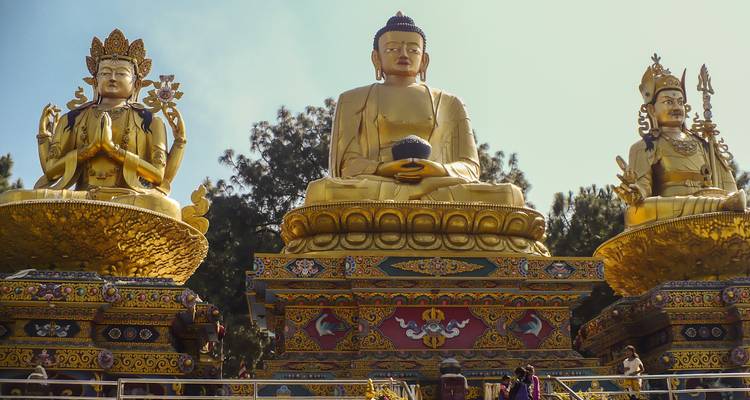 Drie grote gouden boeddhabeelden met ingewikkeld houtsnijwerk.
