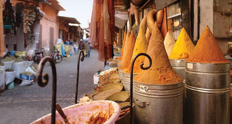 Colorful spice cones and market goods lining a narrow souk alley.