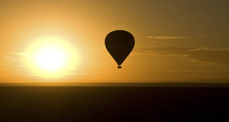 Silueta de un globo aerostático contra un amanecer.