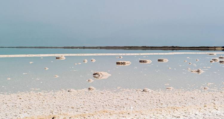 Kristalhelder Dode Zeeoevers met zoutformaties tegen een rustige blauwe horizon.