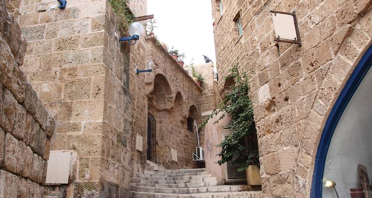 Smalle stenen steeg met versleten trappen en bogen in een oud Mediterraans stadje.