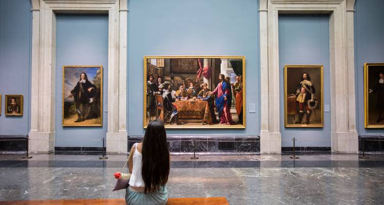 Mujer joven observando cuadros clásicos en una elegante sala de la Galería del Museo del Prado.