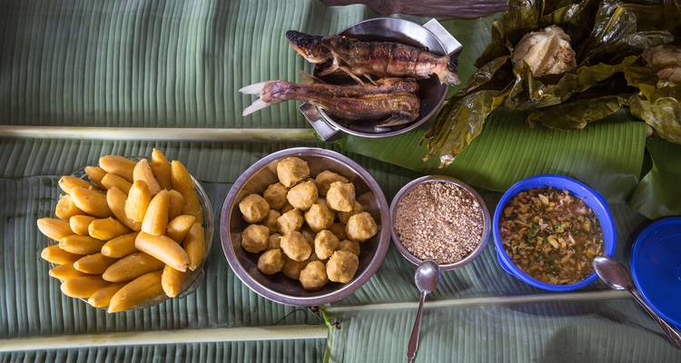 Comida tradicional amazónica servida en hojas de plátano incluyendo maíz, pescado y salsas