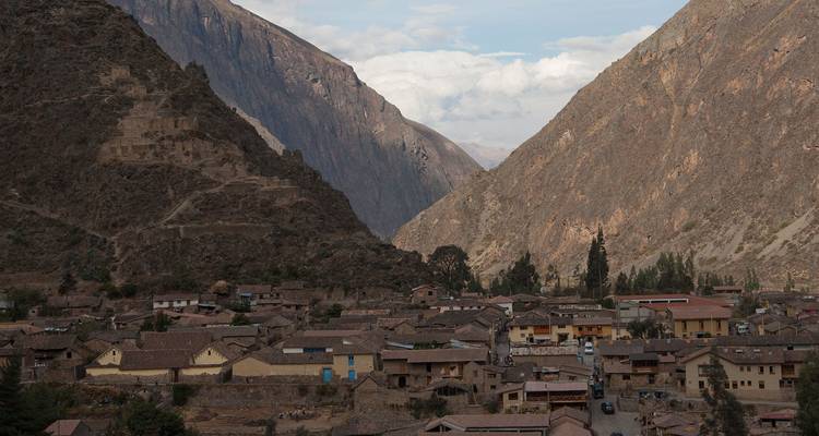 Village andin niché entre des montagnes rocheuses escarpées sous une lumière d'après-midi voilée