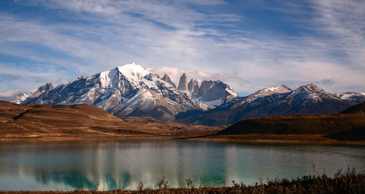 Schneebedeckte patagonische Gipfel spiegelten sich makellos in einem stillen türkisfarbenen See unter gesprenkelten Wolken wider