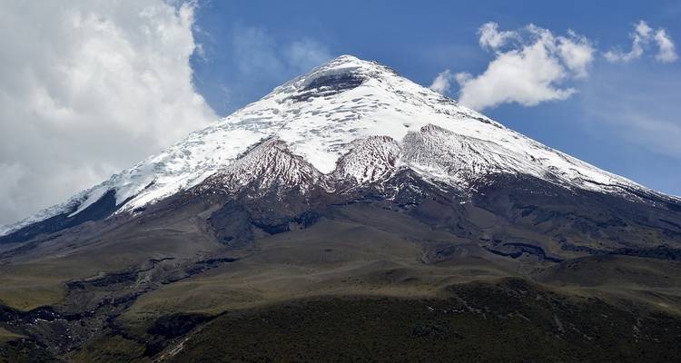 A mountain with a snow-covered peak under a bright blue sky.