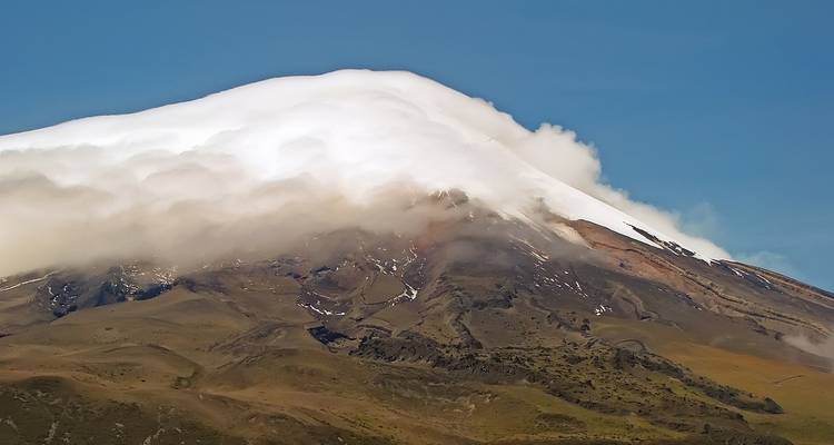A snow-capped mountain with clouds around the summit.