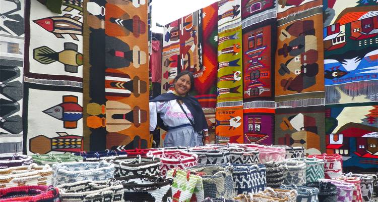 Lächelnde Frau vor handgewebten Wandteppichen.