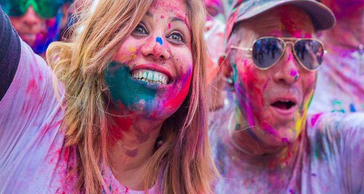 People with colorful powder on faces during a festival.
