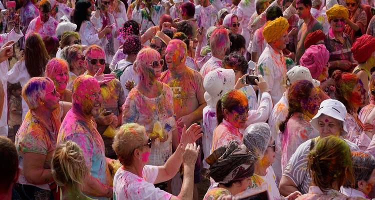 Crowd of people covered in colorful powder celebrating a festival.