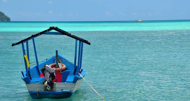 A small boat in crystal-clear turquoise waters.
