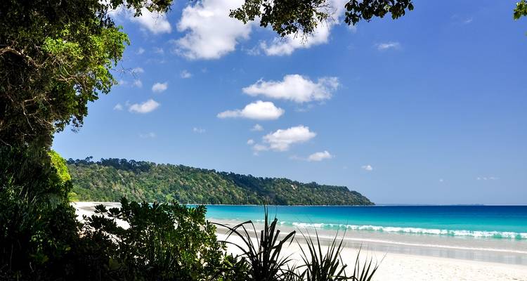 A wide, pristine beach with clear skies and blue waters.