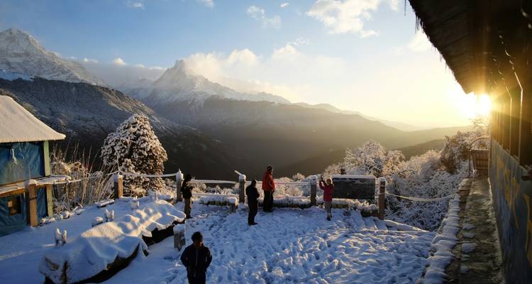 Les enfants et les adultes jouent dans la neige fraîche sur une terrasse de montagne tandis que la lumière dorée du lever de soleil inonde la vallée