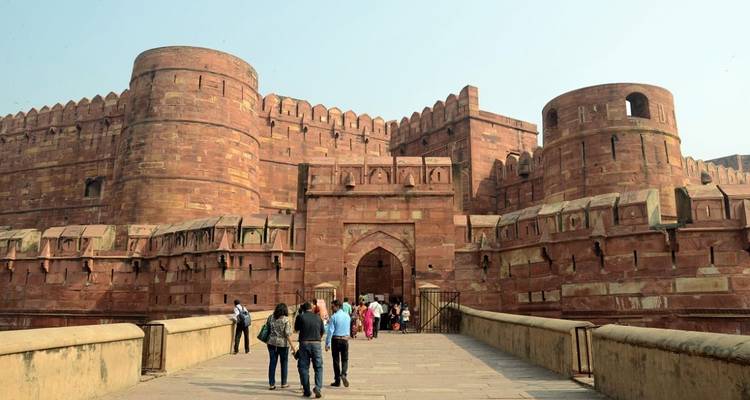 Eingangstor eines großen roten Steinforts mit Menschen, die hineingehen.