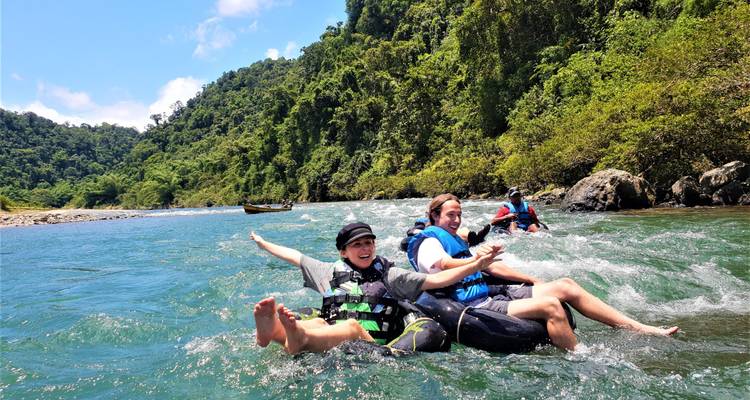 Mensen die tuben op een rivier omgeven door weelderig groen.