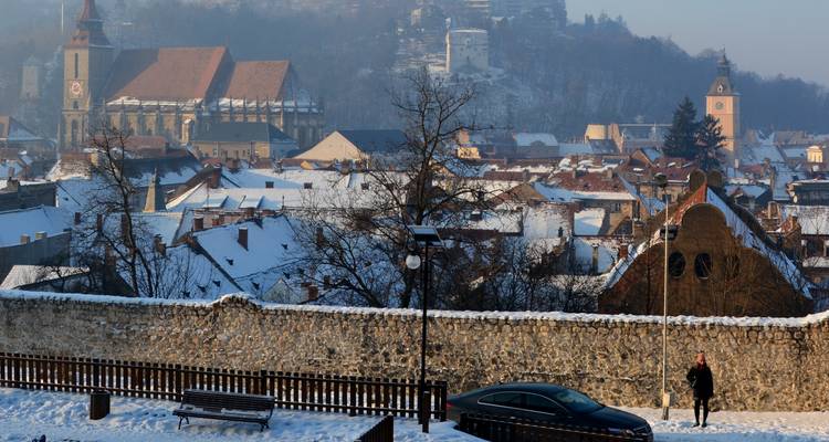 Tejados cubiertos de nieve de Brasov con la gótica Iglesia Negra y las colinas circundantes al amanecer.