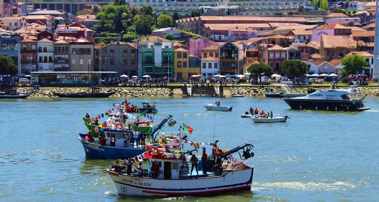 Bateaux décorés pour la fête naviguant sur une rivière avec des bâtiments colorés en arrière-plan