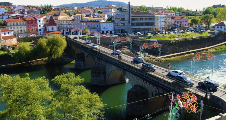 Voitures traversant un pont sur une rivière entourée de bâtiments et d'arbres