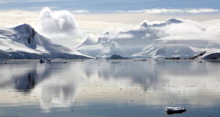 Snow-covered mountain range reflecting in icy waters