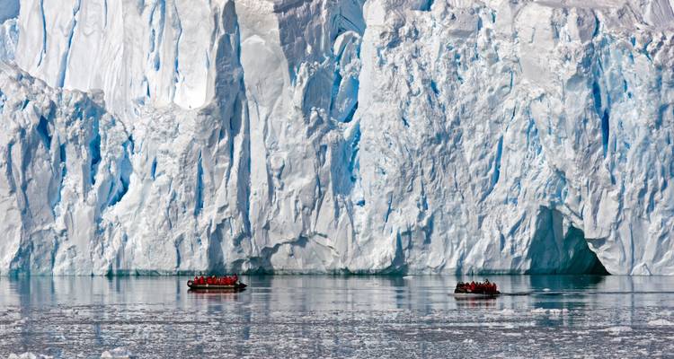 Zodiacs exploring vast icy landscape with towering glaciers