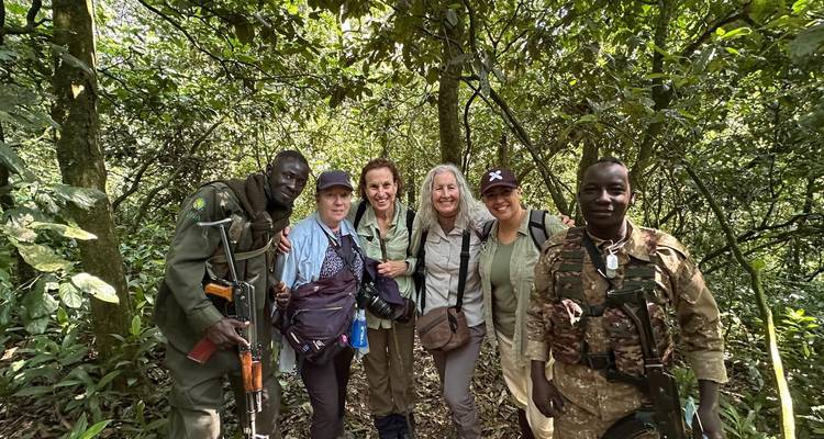 Viajeros y guardabosques armados se toman una foto juntos en la densa selva tropical durante una caminata.