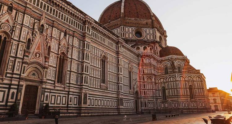Florenz' ikonischer Dom und Baptisterium erstrahlen im sanften Sonnenlicht der Morgendämmerung über einem leeren Platz.