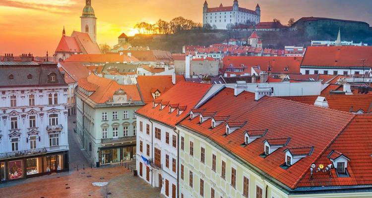 Una vista del amanecer sobre los tejados de tejas de Bratislava con la torre de la Catedral de San Martín y el Castillo de Bratislava en la cima de la colina.