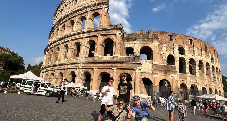 Groupe de touristes posant devant le Colisée historique de Rome.