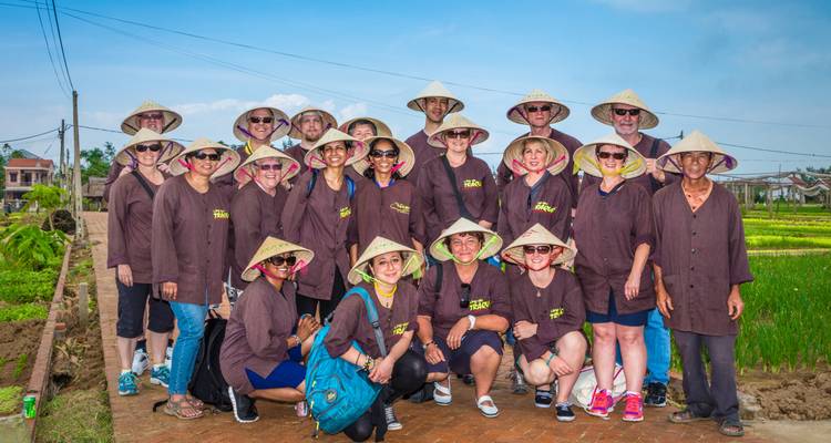 Group of tourists posing in traditional attire in a rural setting.