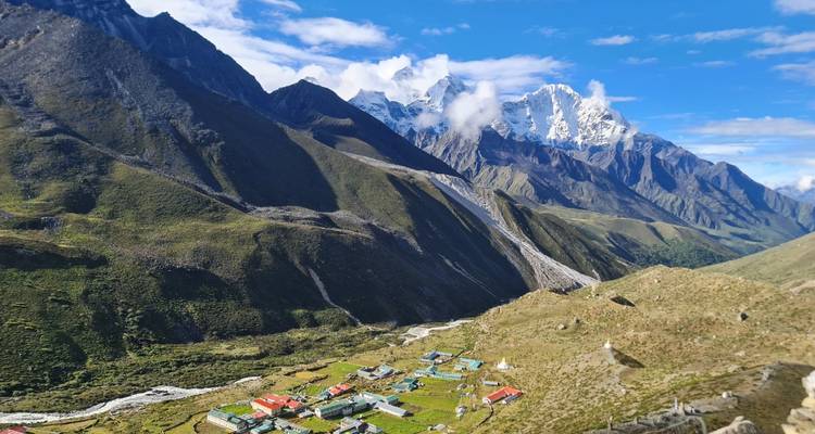 Vogelsperspectief van een Himalaya-bergdorpje met terrassentoppen onder indrukwekkende sneeuwtoppen.