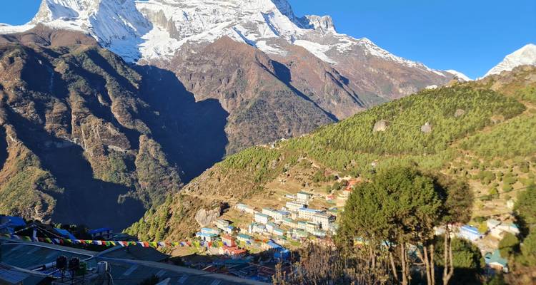 Panoramisch uitzicht over Namche Bazaar, genesteld op een berghelling onder sneeuwbedekte toppen en gebedsvlaggen.