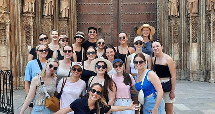 Grand groupe de personnes posant devant une porte historique.
