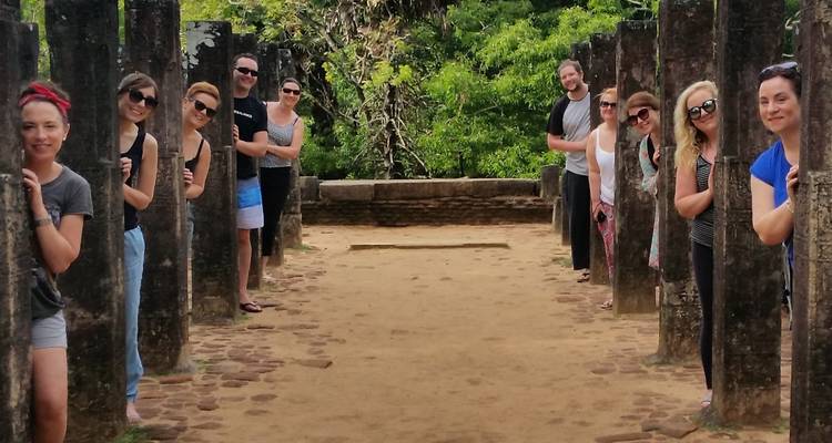 Groupe de personnes posant derrière des colonnes antiques sur un site historique.