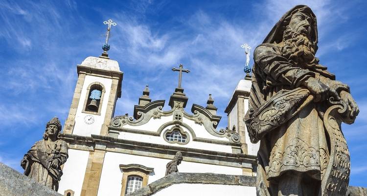 Iglesia histórica con esculturas y un fondo de cielo azul.
