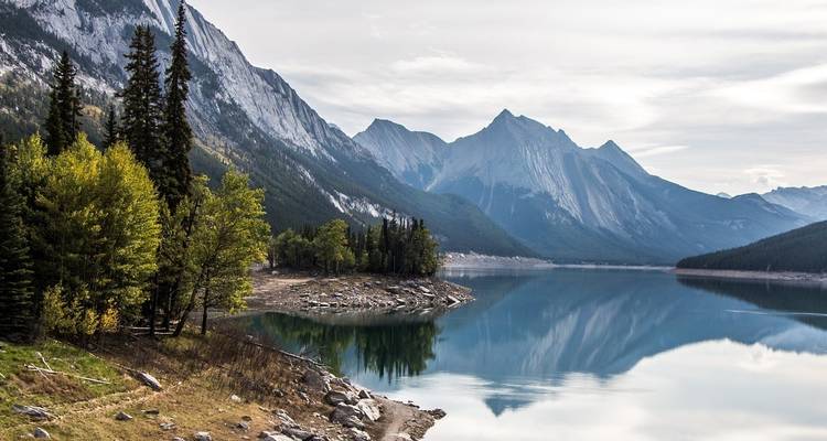 Bergsee mit klaren Spiegelungen und umgebendem Wald.