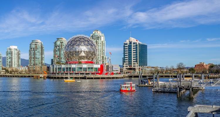 Moderne Stadtlandschaft mit einem markanten kuppelförmigen Gebäude am Wasser.