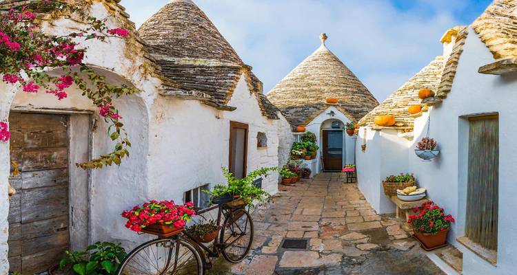 Charming cobbled street with traditional white Trulli houses and flowers.
