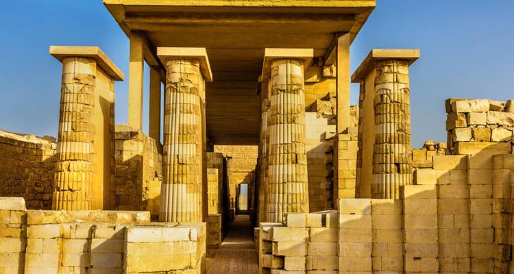 Columnas de piedra iluminadas por el sol con acanaladuras características en el complejo de la Pirámide Escalonada en Saqqara.