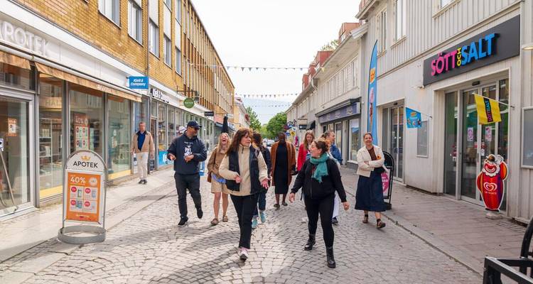 Een groep mensen die een geplaveide straat aflopen met winkels.