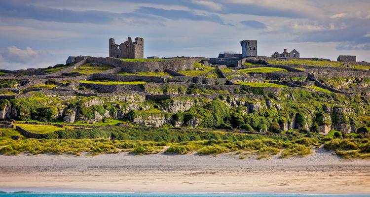 Ancient stone fortifications atop a grassy hill.