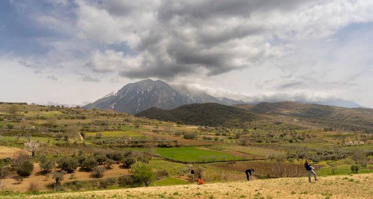 Paysage avec montagne et personnes travaillant dans les champs.