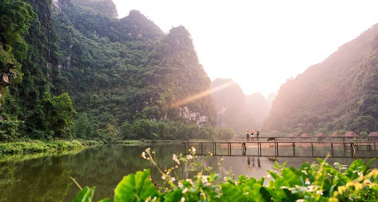 Two people standing on a bridge over a lake with towering limestone formations.