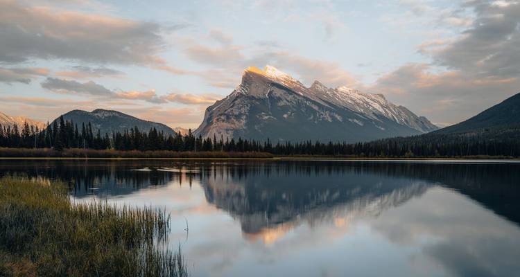 Montagne reflétée dans un lac calme avec une ligne d'arbres en arrière-plan